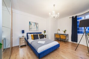 Ein modernes Schlafzimmer mit einem großen Bett, Nachttischen, einem Schreibtisch und einem Stuhl.