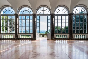 A spacious room with large arched windows, a marble floor, and a view of the outdoors. - Masaccio Apartament in Villa Guinigi (Capannori)
