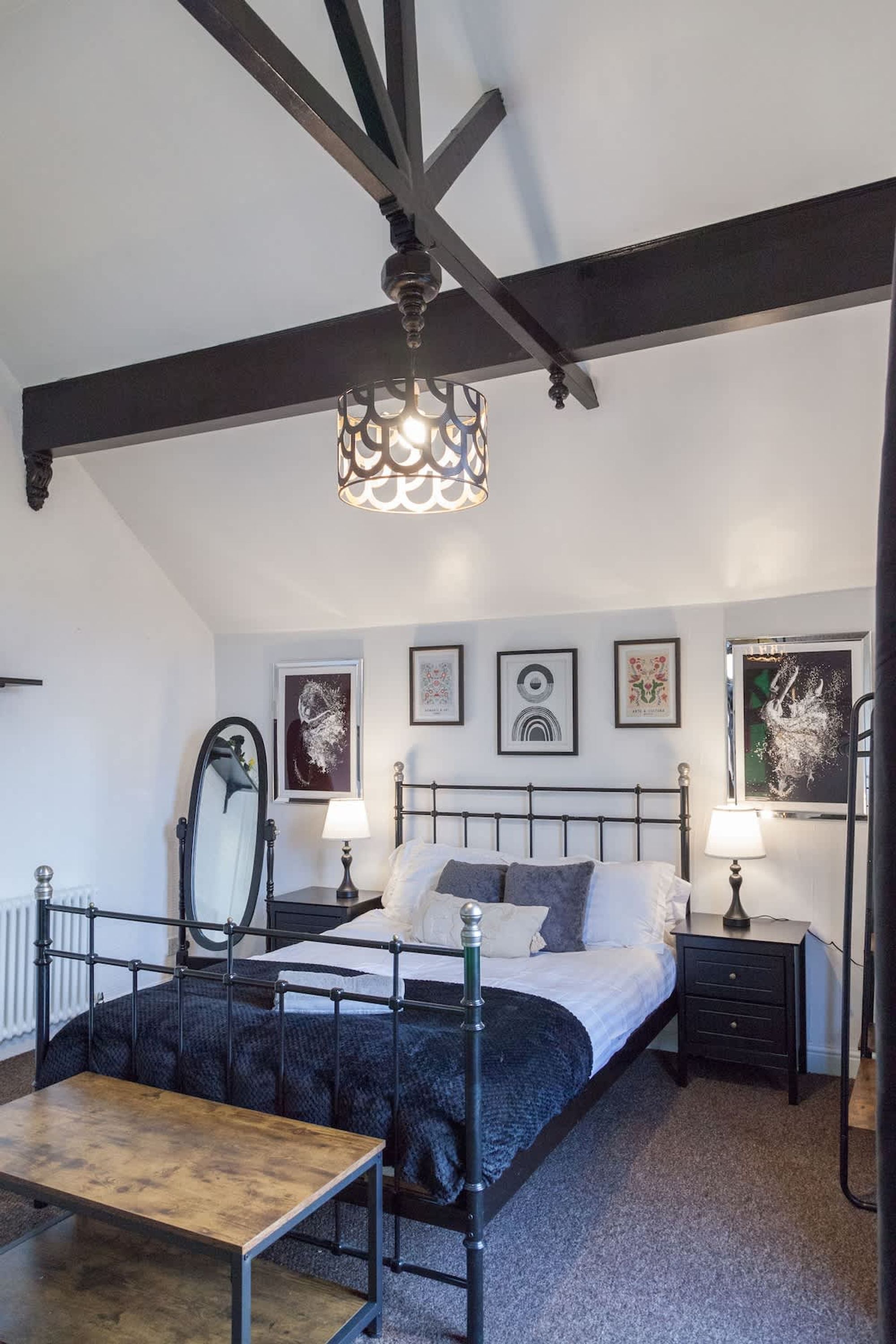 A bedroom with a bed, bedside tables, a mirror, and artwork on the walls.