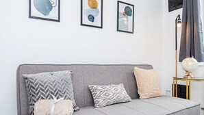 Um sofá cinzento com almofadas estampadas, um globo em cima de uma mesinha e arte abstrata na parede.