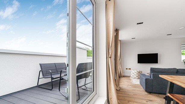 Ein modernes Wohnzimmer mit einer Couch, einem Holztisch und einem an der Wand montierten Fernseher.