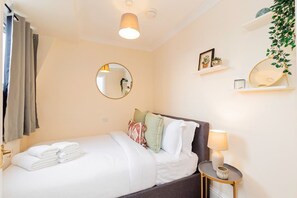 Ein Hotelzimmer mit Bett, Nachttischlampe, Spiegel und einem Regal mit Dekoration.