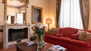 A room with a fireplace, a red sofa, a vase with flowers, a mirror, and a painting on the wall. - Villa di Buona Speranza - Oasis of Serenity (Lucca)