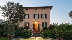 A building with a fountain in front, surrounded by potted plants and a well-kept garden. - Villa di Buona Speranza - Oasis of Serenity (Lucca)