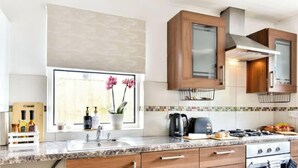 Una cocina moderna con armarios de madera, horno empotrado y ventana con flores.