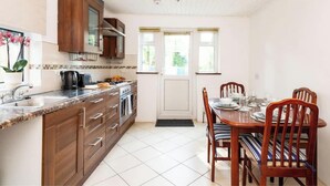Una cocina con armarios de madera, una encimera y un comedor con mesa y sillas.