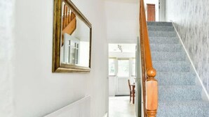 Una escalera con barandilla de madera, un espejo en la pared y suelo de baldosas.