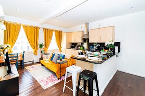 A modern kitchen with wooden cabinets, a black countertop, and a built-in stove. - Stylish 2BR Near Hyde Park Museums Kensington (London)