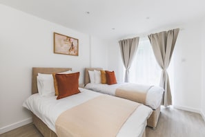 Ein Hotelzimmer mit zwei Betten, einem Bild an der Wand und einem Fenster mit Vorhängen.
