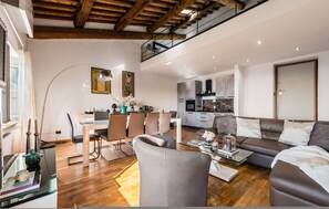 Ein geräumiger Wohnbereich mit Esstisch, Stühlen, einer Couch und einer Küche im Hintergrund.