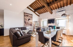 Ein modernes Wohnzimmer mit einer Couch, einem Esstisch, Stühlen und einem großen Gemälde an der Wand.