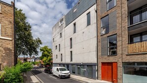 A modern building with a flat roof, large windows, and a red door. - Modern 3beds 3baths in Hackney (London)