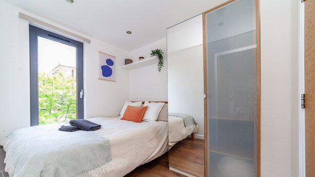 A bedroom with a bed, a sliding door, a window, and a plant. - Modern 3beds 3baths in Hackney (London)