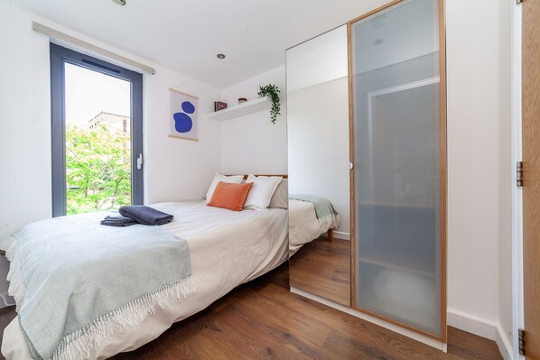 Ein Schlafzimmer mit einem Bett, einer Schiebetür, einem Fenster und einer Pflanze.