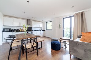 Eine moderne Küche mit weißen Schränken, einem Holzespeisetisch und einem grauen Sofa.