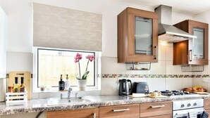 A kitchen with a granite countertop, stainless steel sink, wooden cabinets, and a window with a view of the outdoors. - Omega Hanwell 2nd Floor Ensuite Free Parking (London)