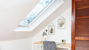 A room with a skylight, a desk, a chair, a lamp, and two framed pictures on the wall. - Omega Hanwell 2nd Floor Ensuite Free Parking (London)