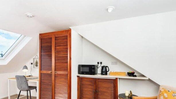 A compact kitchen with a skylight, a microwave, and a kettle on the countertop. - Omega Hanwell 2nd Floor Ensuite Free Parking (London)
