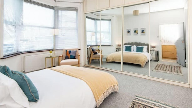 Ein Schlafzimmer mit Bett, Kleiderschrank, Spiegel und Fenster.