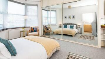 A bedroom with a bed, a wardrobe, a mirror, and a window.