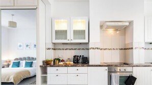 Eine moderne Küche mit weißen Schränken, einer gefliesten Spritzschutzwand und einem eingebauten Backofen.