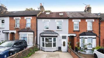A row of terraced houses with a garage on the left, a bay window on the second house, and a white picket fence on the right.