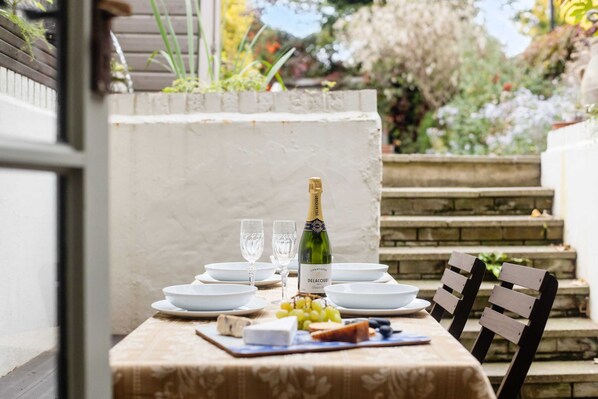 A table set with plates, glasses, a bottle of champagne, cheese, and grapes. - Luxury 1820s Georgian Home 5-min Walk to Station (London)