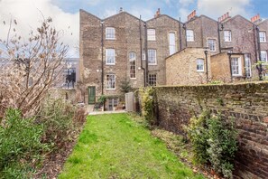 A brick building with multiple windows and a small grassy area in front. - Luxury 1820s Georgian Home 5-min Walk to Station (London)
