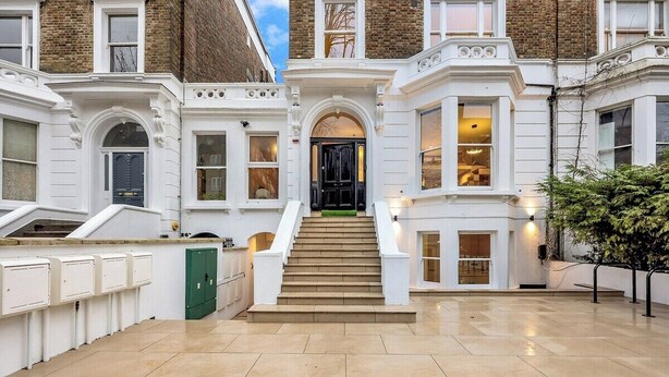 A building with a grand entrance, a staircase leading to the main door, and a well-lit interior. - Spacious Rooftop Studio Flat in London (London)