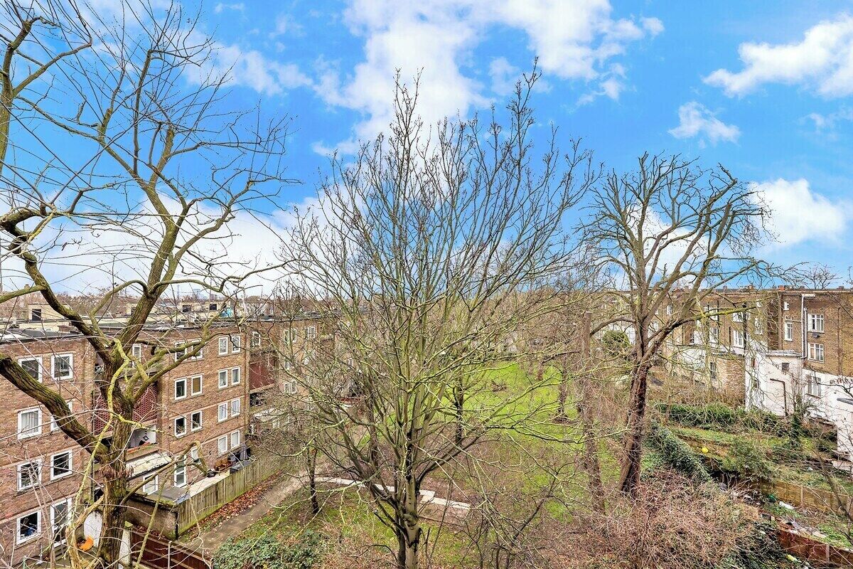 A residential area with brick buildings, a tree, and a clear sky.