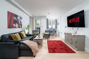 Ein modernes Wohnzimmer mit Sofa, Couchtisch und Fernseher.