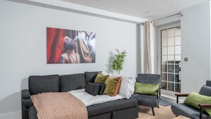Un salon moderne avec un canapé gris, une table basse et un grand tableau abstrait accroché au mur.