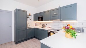 A modern kitchen with grey cabinets, a white countertop, a built-in oven, and a toaster. - Modern Luxurious Retreat in Acton w Great Links (London)