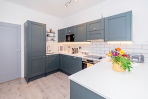 A modern kitchen with grey cabinets, a white countertop, a built-in oven, and a toaster. - Modern Luxurious Retreat in Acton w Great Links (London)