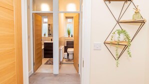 A hallway leading to a bathroom with a geometric wall shelf holding a plant. - Spacious 2BR Flat Summertown Sleeps 7 5 Star (Oxford)