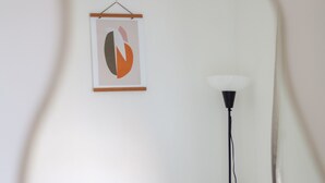 A room with a framed artwork on the wall, a standing floor lamp, and a white chair. - 3 Bed House With Garden in London Fields (London)