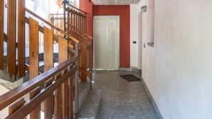 Un corridoio con ringhiera in legno, una porta e pavimento in pietra.