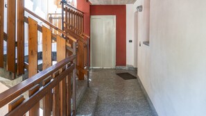A hallway with a wooden railing, a door, and a stone floor. - Palú Elf Den in the heart of Aprica (Aprica)