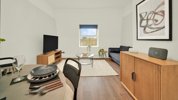 Uma sala de estar moderna com televisão, mesa de jantar e área de estar.