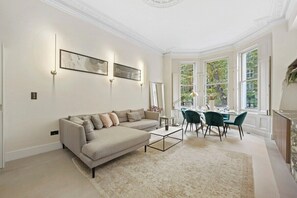 Ein modernes Wohnzimmer mit Sofa, Couchtisch und Essbereich mit Stühlen und einem Tisch.