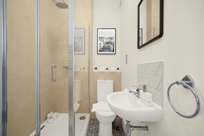Ein modernes Badezimmer mit Duschkabine aus Glas, einem weißen Waschbecken und einer Toilette.