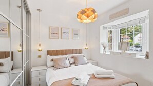 Een netjes ingerichte slaapkamer met een groot bed, nachtkastjes, een kledingkast en een raam met uitzicht.