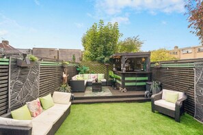 Eine Terrasse mit Sitzgelegenheiten, einer kleinen Bar und einem grünen Rasen.