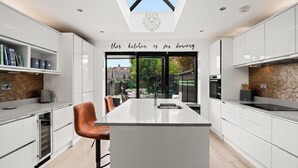 Een moderne keuken met een centraal eiland, witte kastjes en een dakraam.