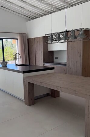 A modern kitchen with a wooden bench, a large window, and a pendant light. - 4-bedroom villa with private pool in Armação de Pêra (Armação de Pêra)