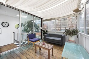 Ein modernes Wohnzimmer mit Glastisch, einer Couch, einem Sessel und einem Blumentopf.