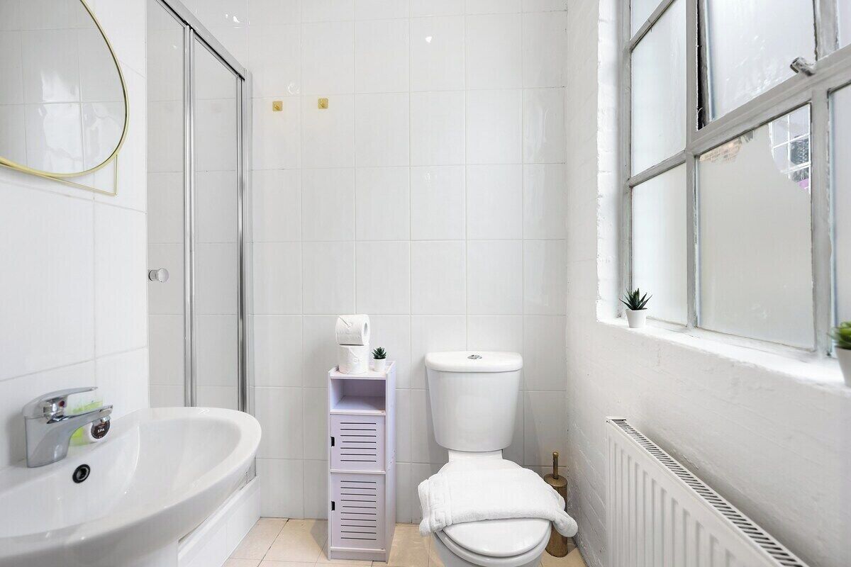Et badeværelse med badekar, toilet og et vindue.
