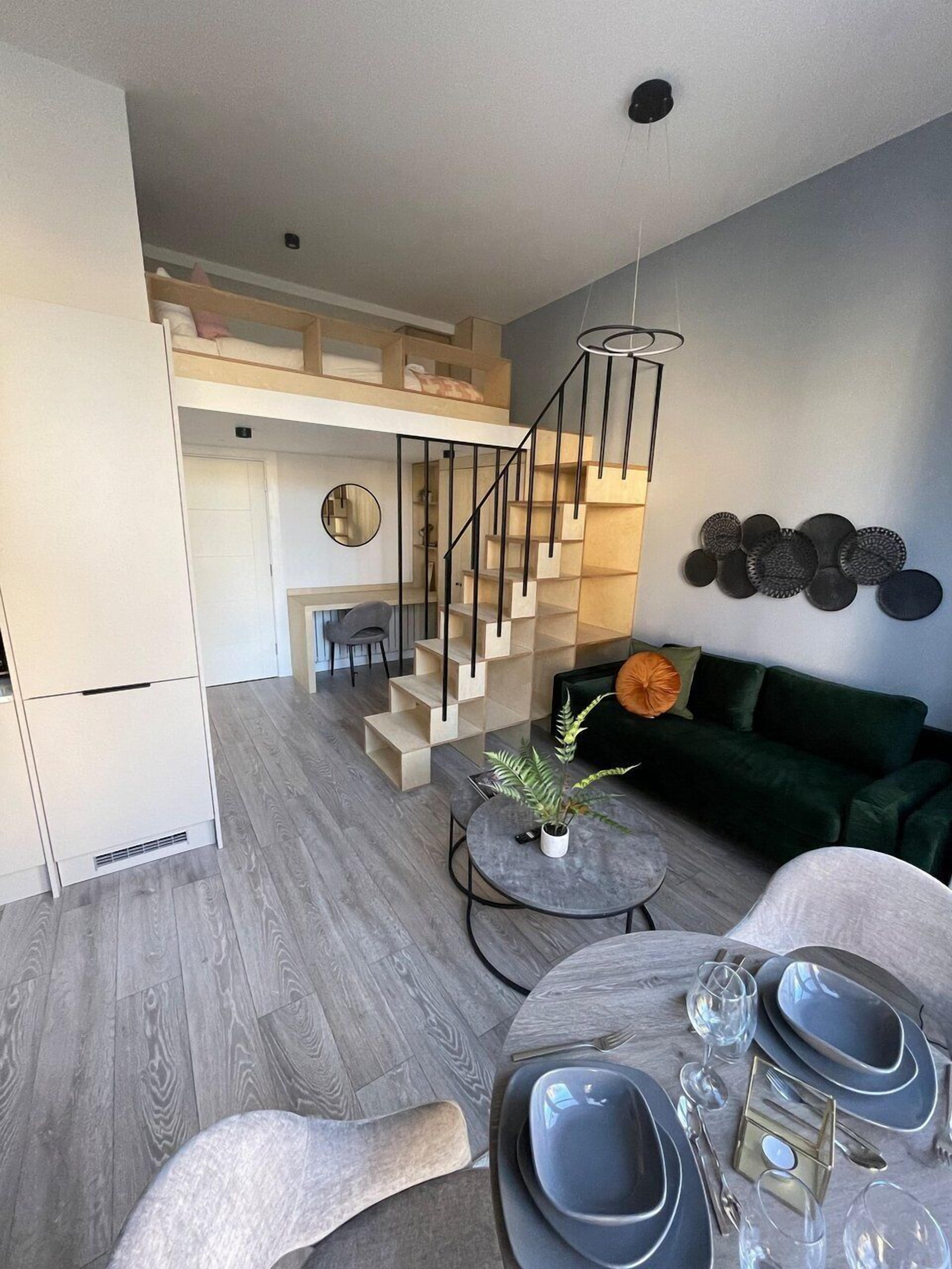 Un espace de vie moderne comprenant un escalier, un coin repas et un canapé vert.