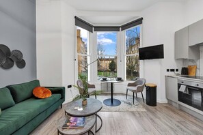 Ein modernes Wohnzimmer mit einem grünen Sofa, einem runden Couchtisch und Blick ins Freie.