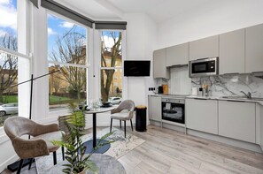 Eine moderne Küche mit großem Fenster, Flachbildfernseher und eingebautem Backofen.